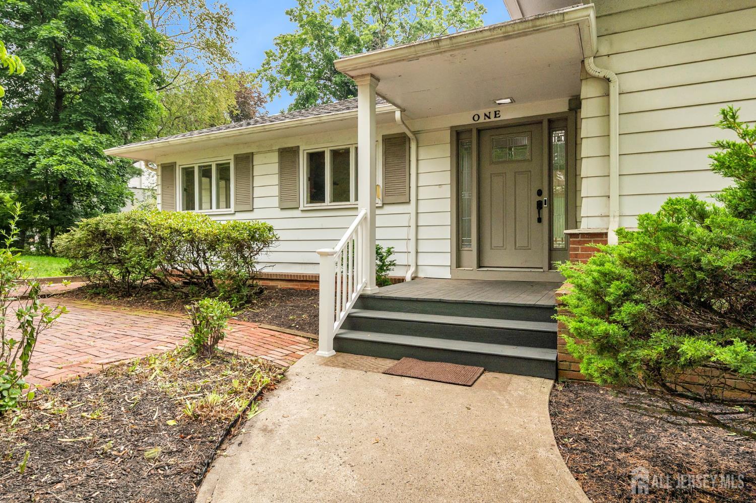 Located in a prestigious enclave, this 3 bedroom home sits on a premium corner lot surrounded by mature trees. A circular driveway, hardwood floors and generous, practical layout add to its appeal. The oversized eat-in kitchen is at the heart of this home, joined by a formal dining room and a light-filled living room with floor-to-ceiling windows and classic fireplace. This level also features additional flex space ideal for a home office, 4th bedroom or playroom. A few steps up, tucked away from the main living area, you will find the primary suite with ensuite bath and two additional bedrooms. A wide full-size staircase leads to the walk-out basement, making the lower level feel like a true extension of the home. Here, you'll find an expansive family room with tall windows, abundant natural light, a second fireplace, and additional room for guests, home office, gym or whatever best suits your needs. Ideally located near major routes, Rutgers University, SHI Stadium, shopping and local hospitals, yet removed from the activity in one of the area's hidden gems.